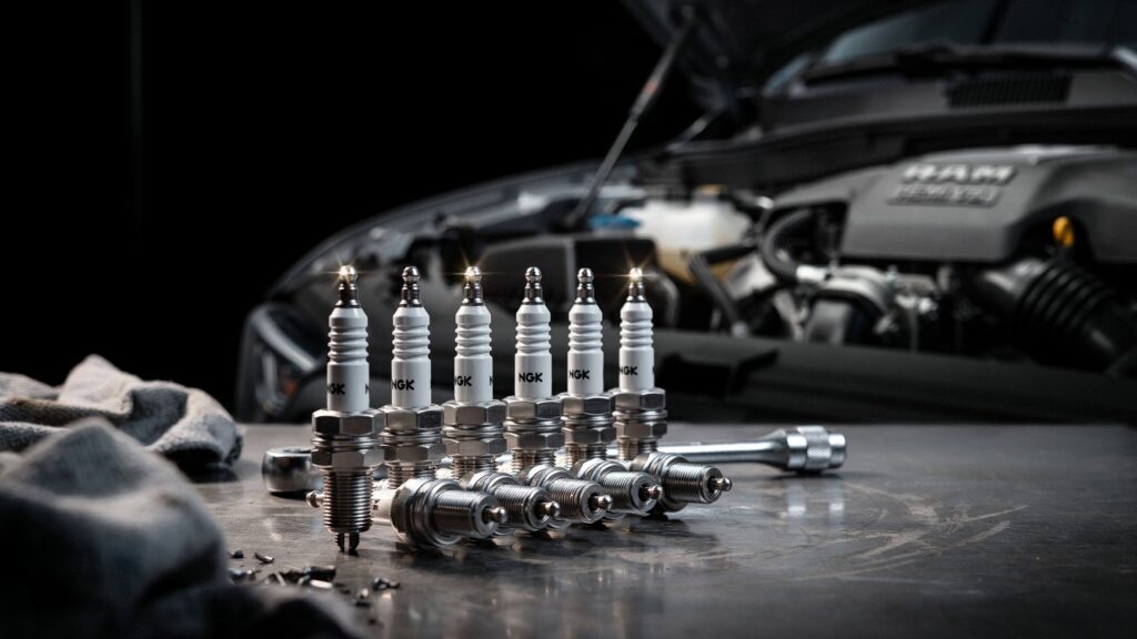 Best spark plugs for Ram 1500 – set of NGK iridium spark plugs with installation tools in front of a Ram 1500 HEMI engine bay